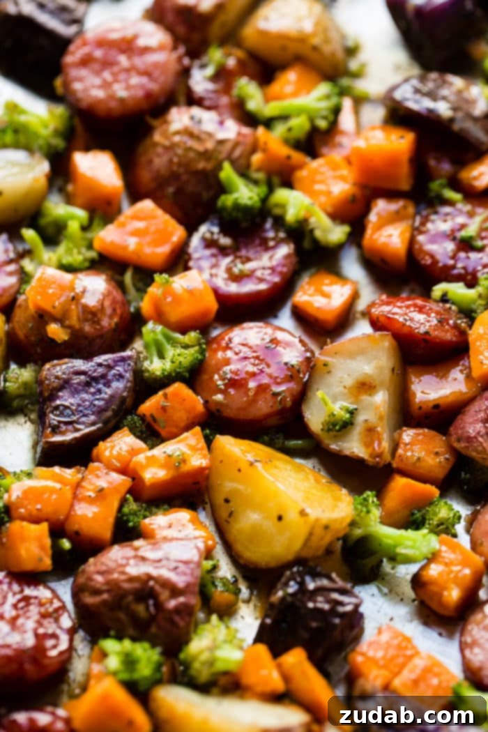 Sticky Honey Garlic Kielbasa Skillet 6 Close-up view of sliced kielbasa and root vegetables on a sheet pan, seasoned and ready for the oven.