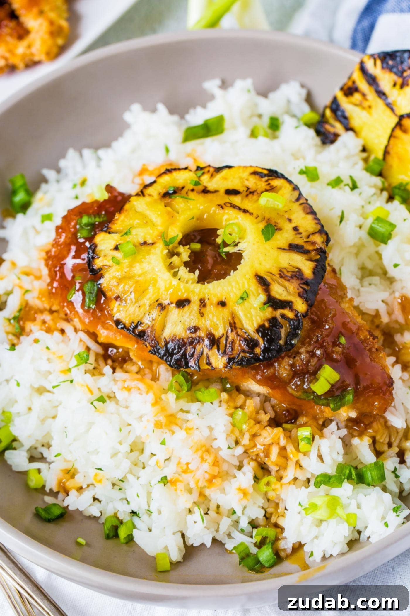 Speedy Sweet & Sour Pineapple Chicken 6 A bowl of white rice topped with breaded chicken sticky sauce chicken like sweet and sour sauce then a beautiful piece of grilled pineapple on top, highlighting a perfect quick dinner