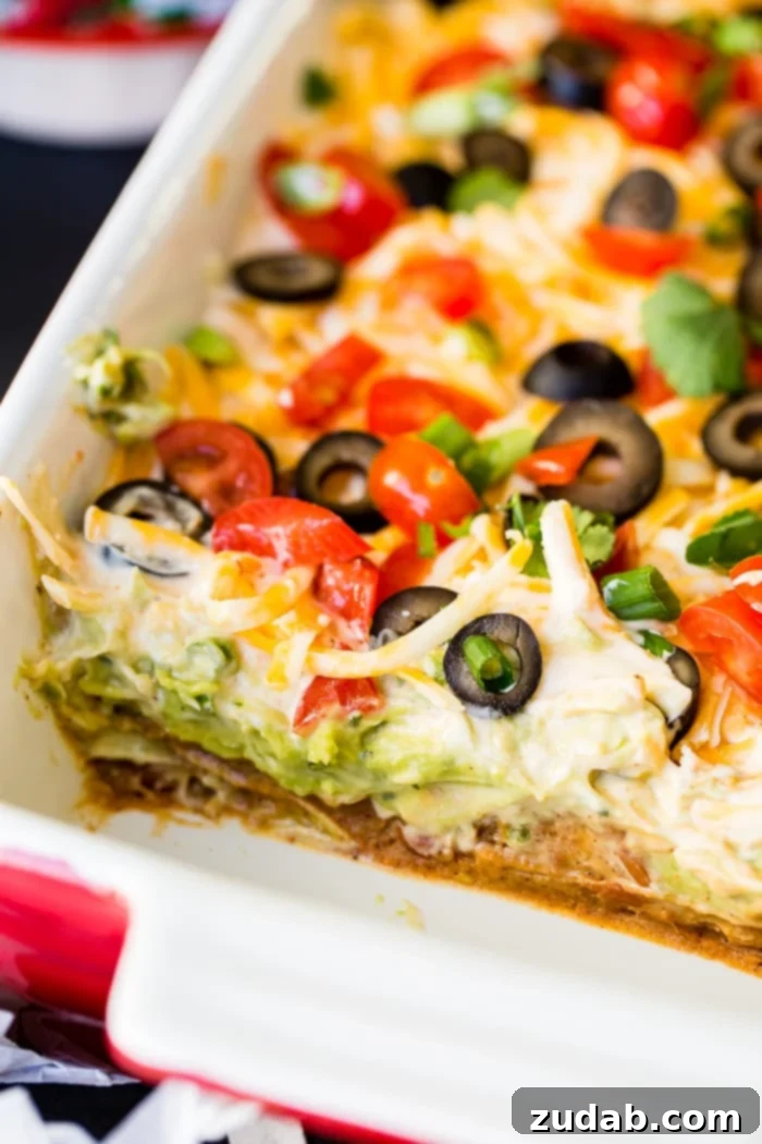 Ultimate Fiesta 7-Layer Dip 7 A close-up of a pan of seven layer dip, artfully topped with a generous layer of sliced black olives, showcasing the rich textures and vibrant colors of each component, ready for serving.