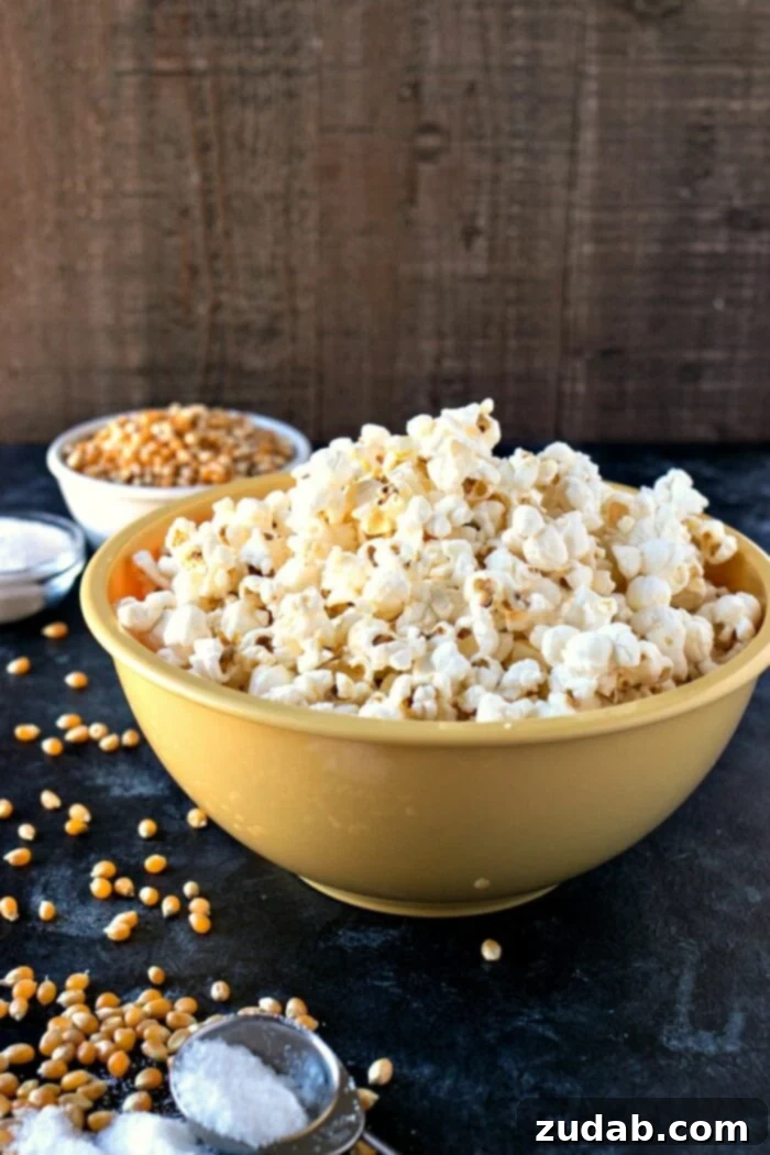 Tangy Salt and Vinegar Popcorn 2 A big yellow bowl of Salt & Vinegar Popcorn with kernels on the side, highlighting the crunchy texture and appealing color. This healthy snack is perfect for parties or a late-night treat.