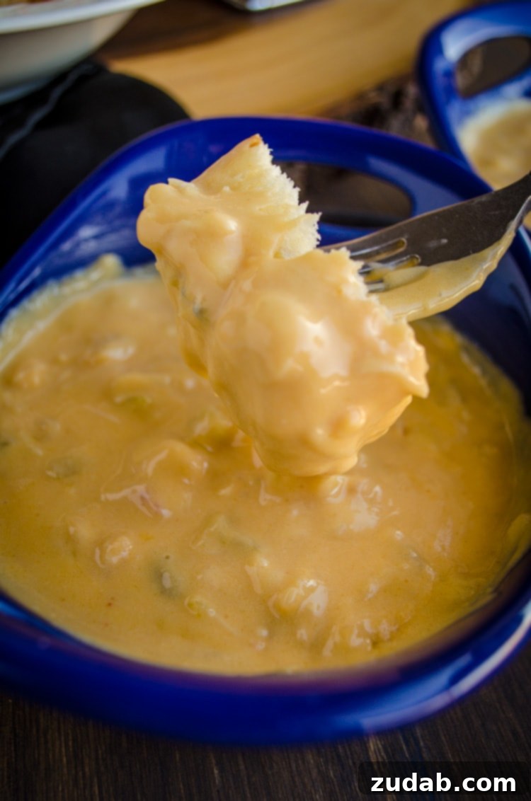 Ultimate Slow Cooker Cheesy Lobster Shrimp Crab Dip 8 A closeup of Cheesy Lobster Shrimp and Crab Dip on a bread cube held by a fork.