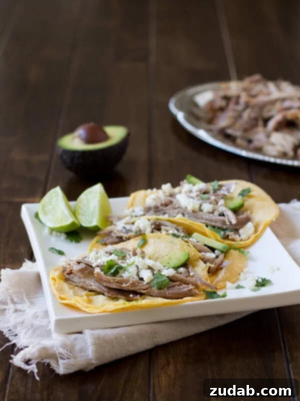 Juicy pork carnitas tacos are simply made in a crockpot with just a few ingredients that everyone has on hand and they turn out perfect every time! ohsweetbasil.com A spread of delicious pork carnitas tacos on a wooden board, highlighting their simple preparation and irresistible appeal.