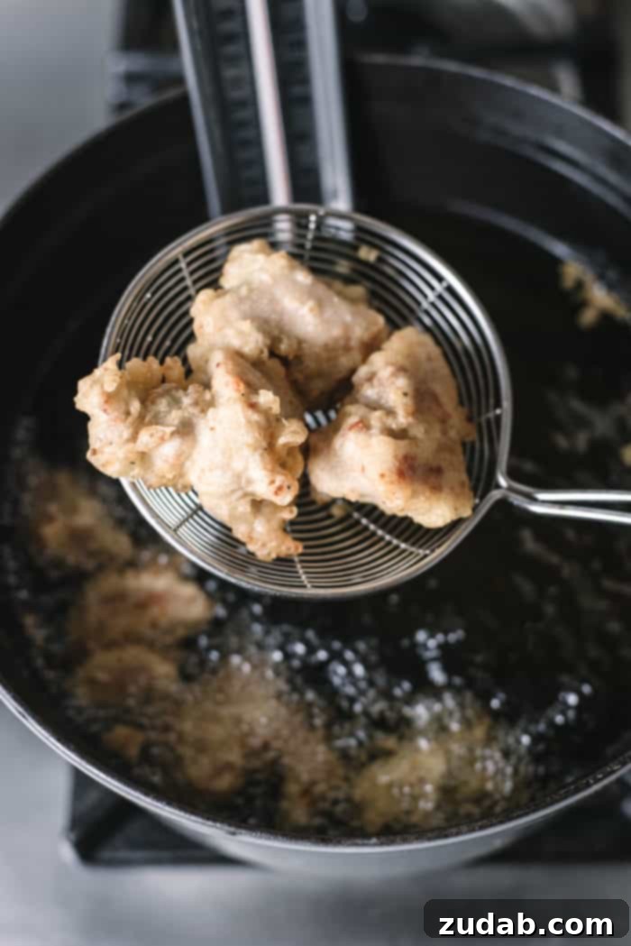 Crispy Korean Fried Chicken 4 Four pieces of freshly double-fried Korean chicken cooling on a wire rack, showing their golden-brown and crispy exterior.
