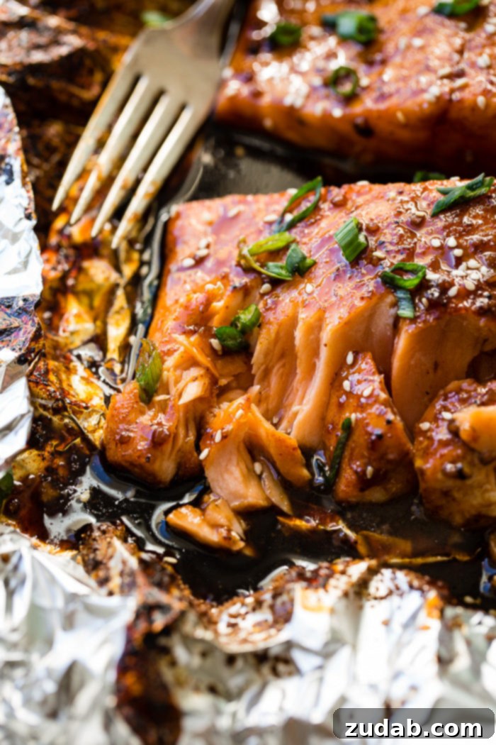 Two delicious salmon fillets, glazed with Asian sticky sauce, topped with green onions and sesame seeds, beautifully arranged in foil.