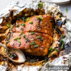 A dish of Asian Sticky Salmon in Foil, garnished with green onions and sesame seeds.
