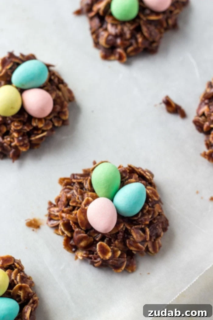 Hoppy Easter Nest Treats 3 Easter nest cookies with miniature chocolate eggs on a cookie sheet, ready for chilling. A simple and festive Easter dessert.