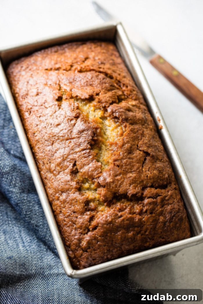 A beautiful loaf of banana bread with sour cream sitting on a blue denim napkin 