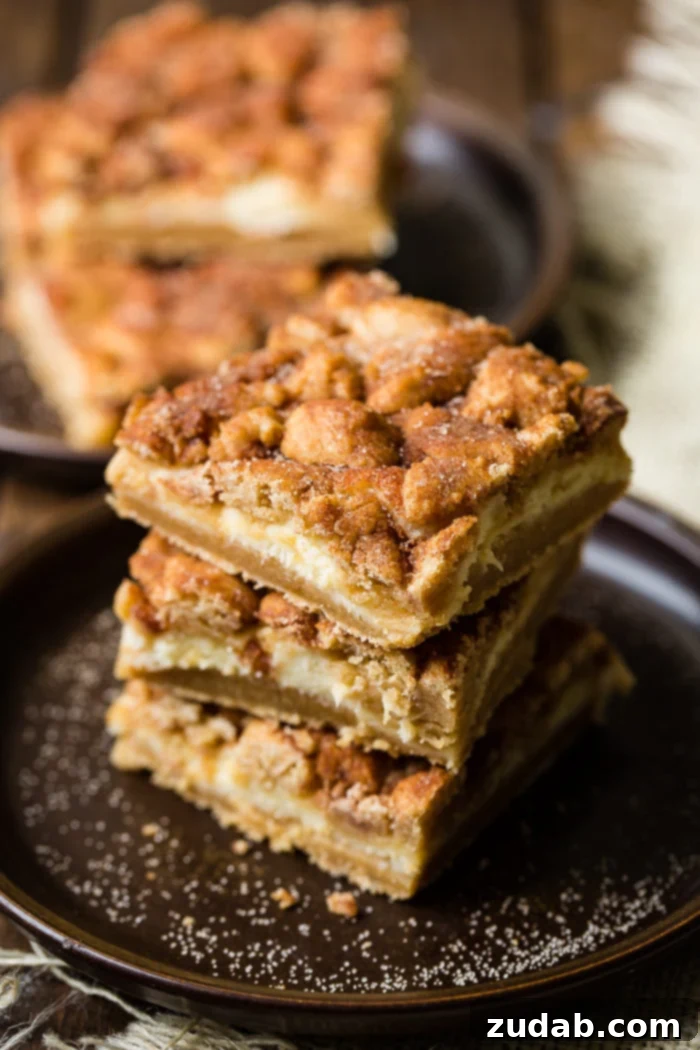Cinnamon Dream Cheesecake Bars 4 stack of three snickerdoodle bars on dark plate