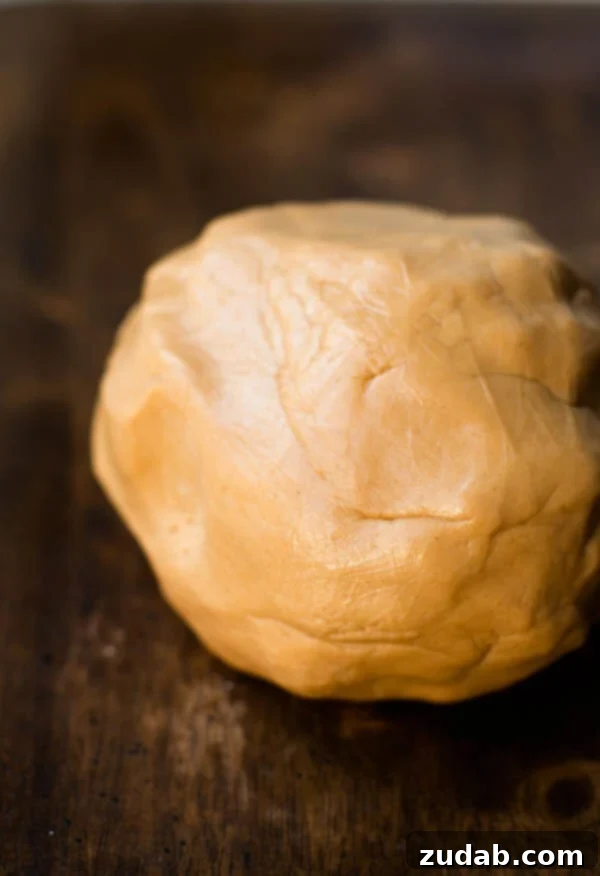 Experience the joy of edible peanut butter playdough – the best and most delicious recipe for kids' sensory play, made with just a couple of ingredients. A vibrant ball of delicious and easy edible peanut butter playdough rests invitingly on a rustic wooden table, ready for imaginative play.