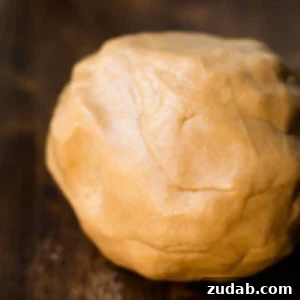 Delicious rolled up ball of edible peanut butter playdough on a wooden table.