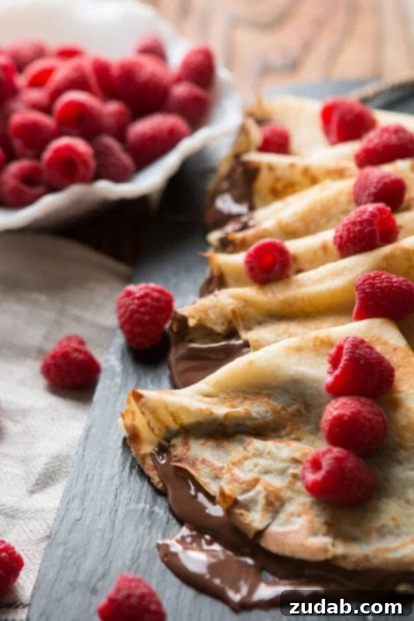 Generously spread Nutella on a warm crepe, garnished with fresh raspberries