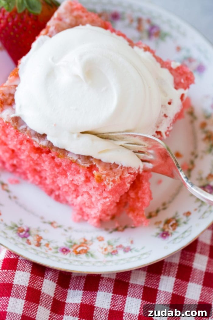 Wobbly Strawberry Dream Cake 4 A picture taken from over the top of a slice of pink strawberries and cream jello cake with a dollop of whipped cream