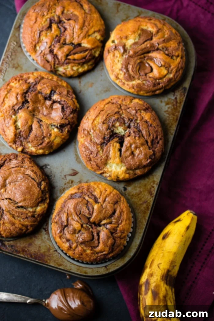 Nutella-Marbled Banana Muffins 4 A muffin tin filled with jumbo Nutella banana muffins, ready to be baked, showcasing the preparation process of these delicious homemade treats.