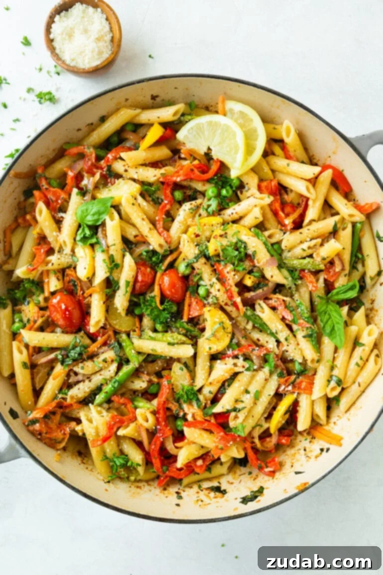 A beautifully arranged serving bowl of pasta primavera, adorned with fresh herbs and bright lemon slices, highlighting its vibrant, fresh ingredients.