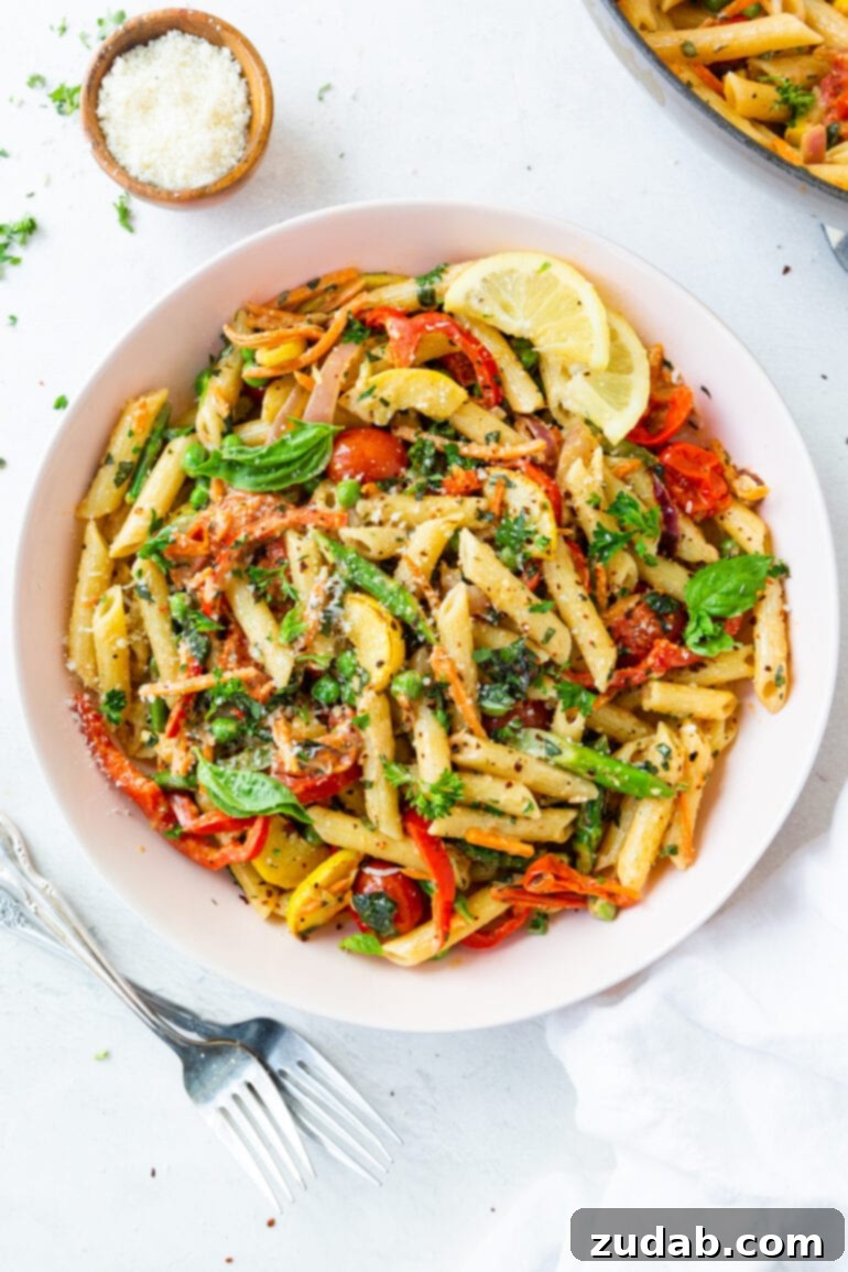 A large serving bowl filled with vibrantly colored Pasta Primavera, showcasing a generous mix of fresh vegetables and penne pasta in a creamy sauce.