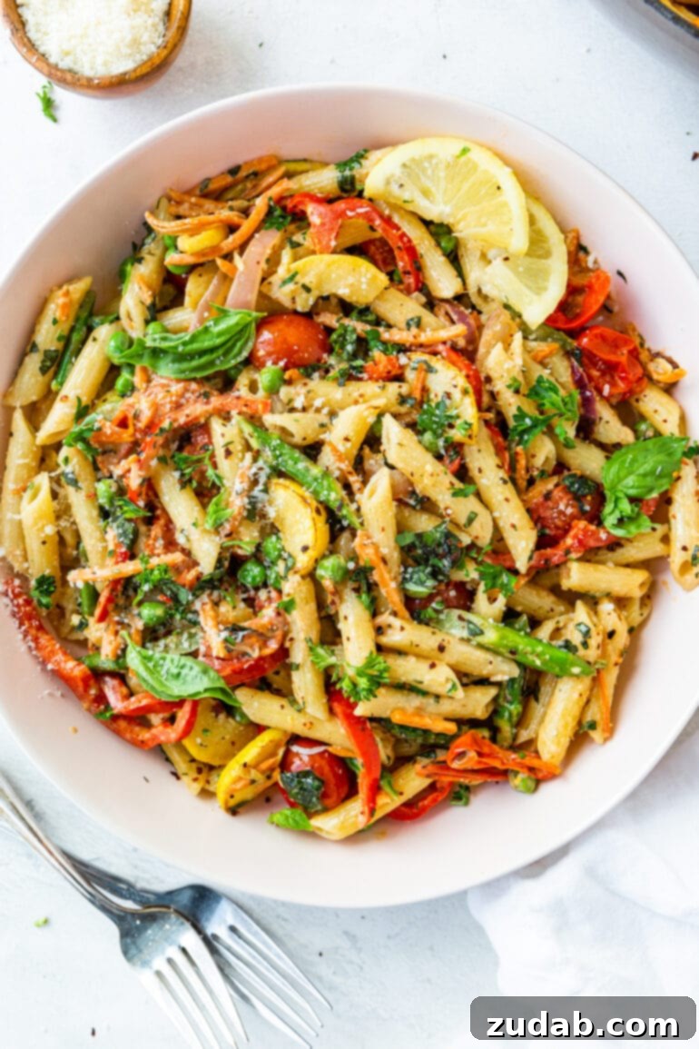 A rustic white serving bowl filled with perfectly cooked penne pasta and a vibrant assortment of fresh sautéed vegetables, showcasing the natural beauty of the ingredients.