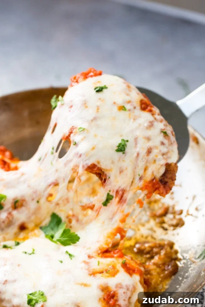 Speedy Weeknight Chicken Parmesan 4 A golden-brown breaded chicken cutlet, generously topped with melted, gooey mozzarella cheese, being carefully lifted from a baking dish with a spatula, ready to be served. This quick and easy shortcut chicken parmesan offers ultimate satisfaction.