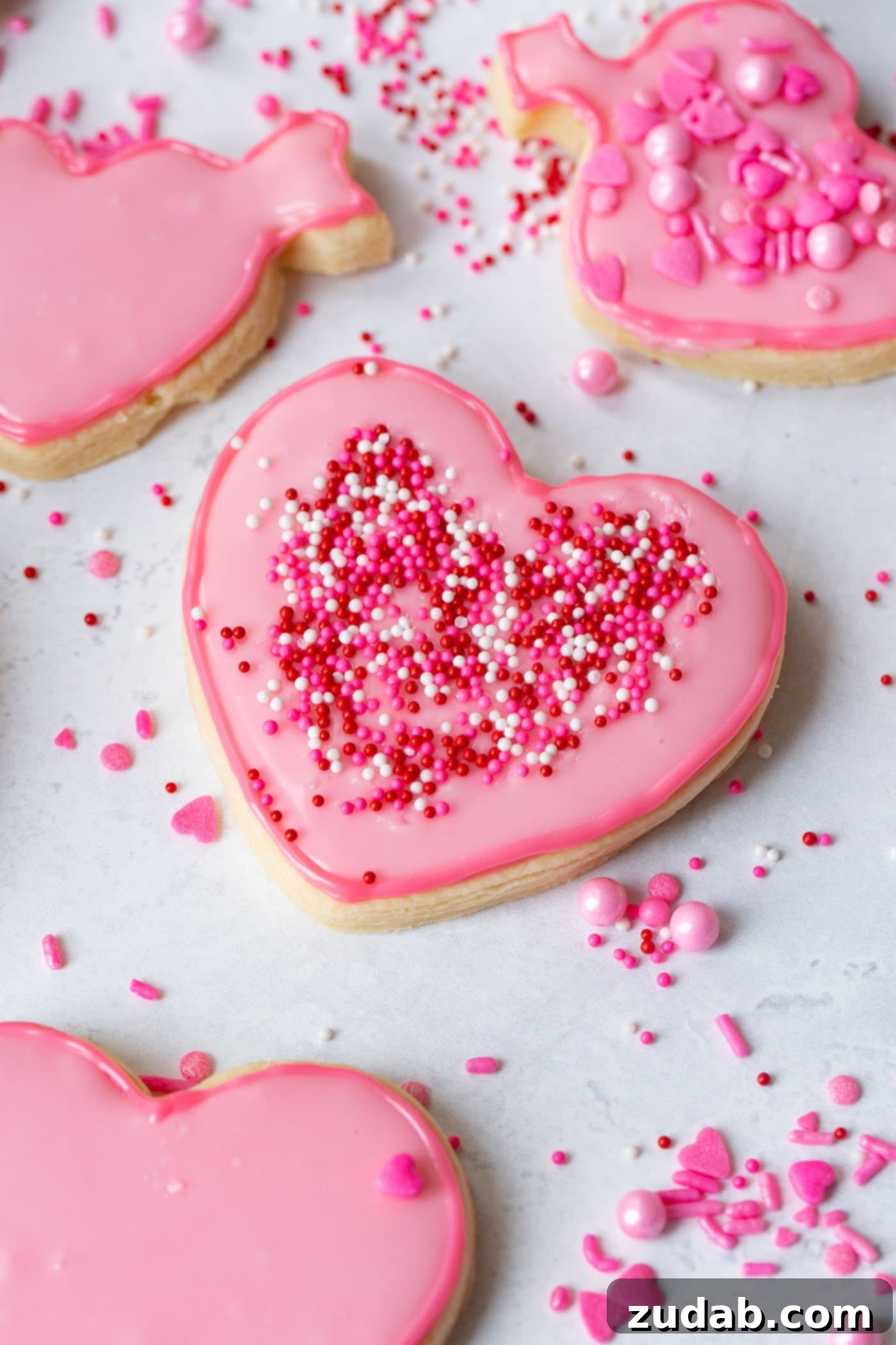 a pink heart sugar cookie with sprinkles