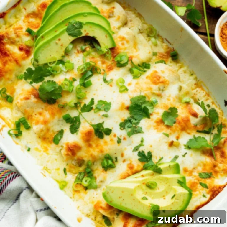 Simple and Delicious Cheesy Chicken Enchiladas 3 a photo of a baking dish full of golden baked cheesy chicken enchiladas topped with sliced avocado, fresh cilantro and chopped scallions