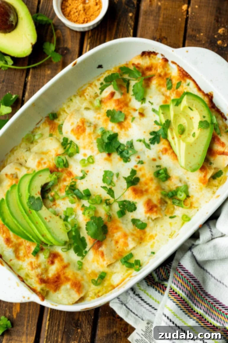 Simple and Delicious Cheesy Chicken Enchiladas 9 a photo of a large casserole dish full of cheesy white chicken enchiladas topped with chopped cilantro and sliced avocado