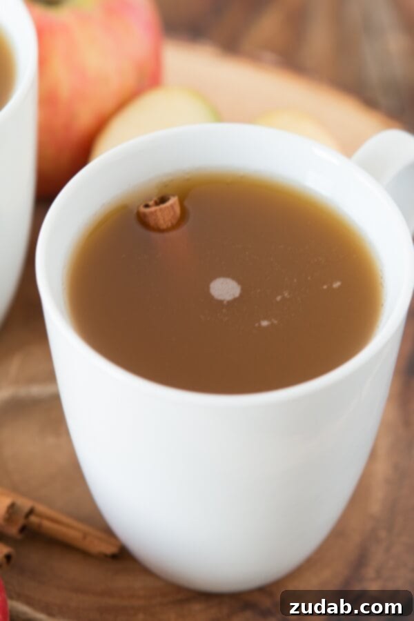 Homemade wassail served in glass mugs, garnished with orange slices and cinnamon sticks