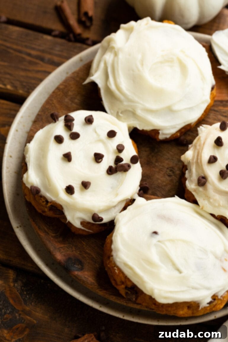Cozy Pumpkin Chocolate Chip Cookies with Cream Cheese Frosting 6 a photo of a tray of four chocolate chip pumpkin cookies with cream cheese frosting with two of them sprinkled with chocolate chips
