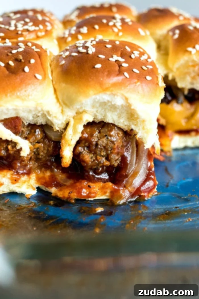 Effortless Smoky BBQ Meatball Sliders 5 Close-up shot of assembled BBQ meatball sliders in a Pyrex dish, ready for baking, showcasing the buttery topping and sesame seeds.