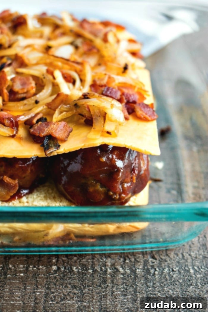 Effortless Smoky BBQ Meatball Sliders 7 A baking tray showing the initial assembly of BBQ meatball sliders with the bottom buns, sauced meatballs, and cheese slices ready for other toppings.