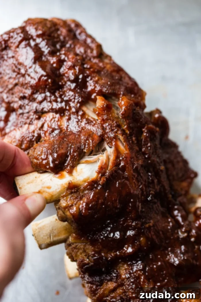 Fall-Off-The-Bone Instant Pot BBQ Ribs 3 A close-up shot of a plate piled high with perfectly cooked Smoky BBQ Instant Pot Ribs, glazed with sauce, showcasing the incredible tenderness as meat effortlessly pulls from the bone.