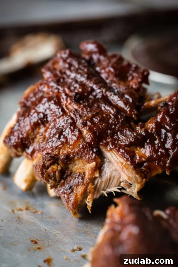Fall-Off-The-Bone Instant Pot BBQ Ribs 6 A baking sheet filled with a magnificent rack of Smoky BBQ Instant Pot Ribs, richly coated in sauce and ready to be carved, showcasing their perfect tenderness.