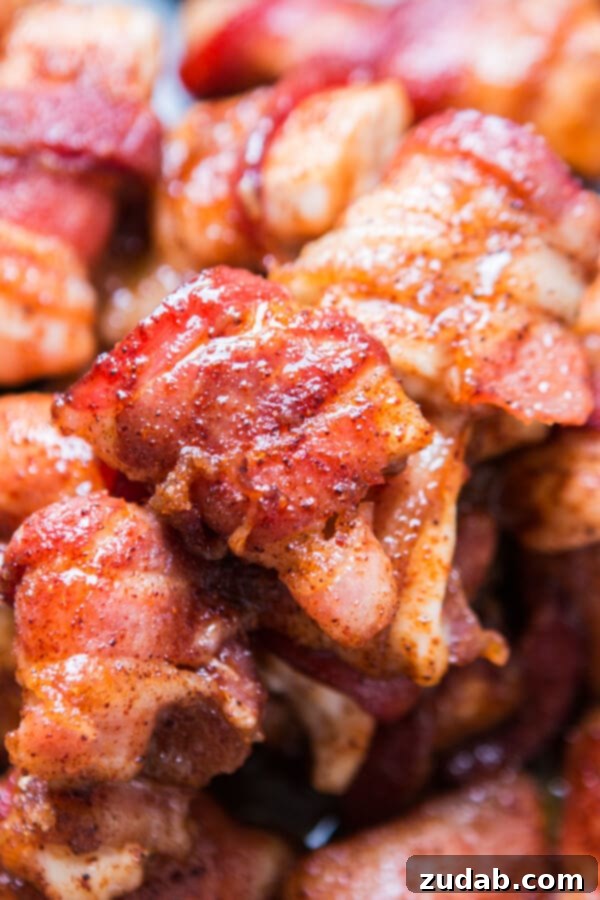 Juicy chicken breast wrapped in crispy bacon with a sweet and smoky glaze. Close-up of golden-brown baked bacon-wrapped chicken pieces, highlighting the crispy bacon and glistening glaze.