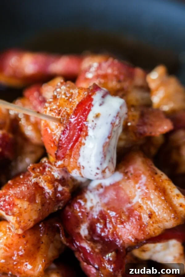 Perfect appetizer: Bacon-wrapped chicken with a sweet glaze. Close-up of a single piece of bacon-wrapped chicken, perfectly skewered with a toothpick, ready for an appetizer spread.