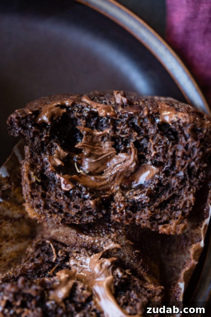 Molten Nutella Double Chocolate Banana Muffins 5 A freshly baked Nutella-stuffed chocolate banana muffin with a visible Nutella swirl on top.