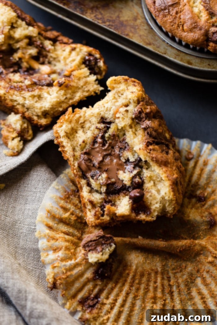 Peanut Butter Banana Muffins with a Gooey Nutella Center 5 A perfectly sliced Nutella-stuffed peanut butter banana muffin, revealing its creamy, molten center, resting elegantly on an open muffin liner.