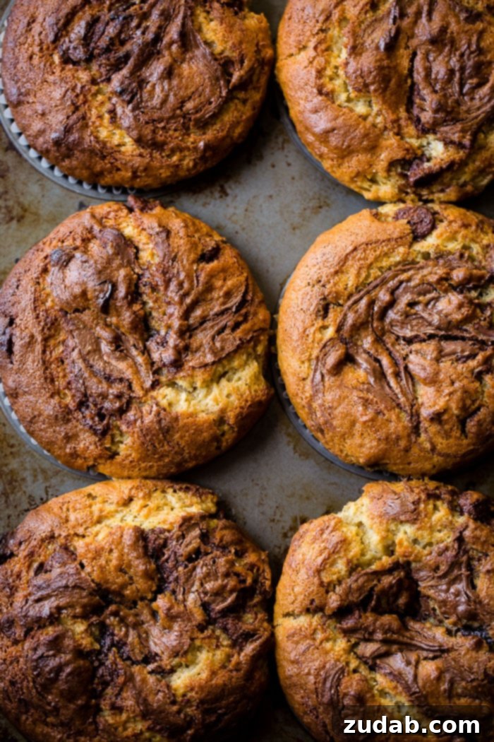Peanut Butter Banana Muffins with a Gooey Nutella Center 9 A beautiful display of peanut butter banana muffins, loaded with chocolate chips, peanut butter chips, and featuring a generous Nutella swirl on top.