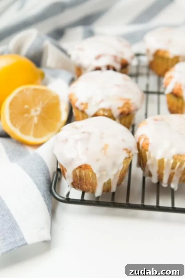 Perfectly Glazed Lemon Poppy Seed Muffins Cooling Warm glazed lemon poppy seed muffins arranged on a cooling rack, glistening with sweet lemon glaze.