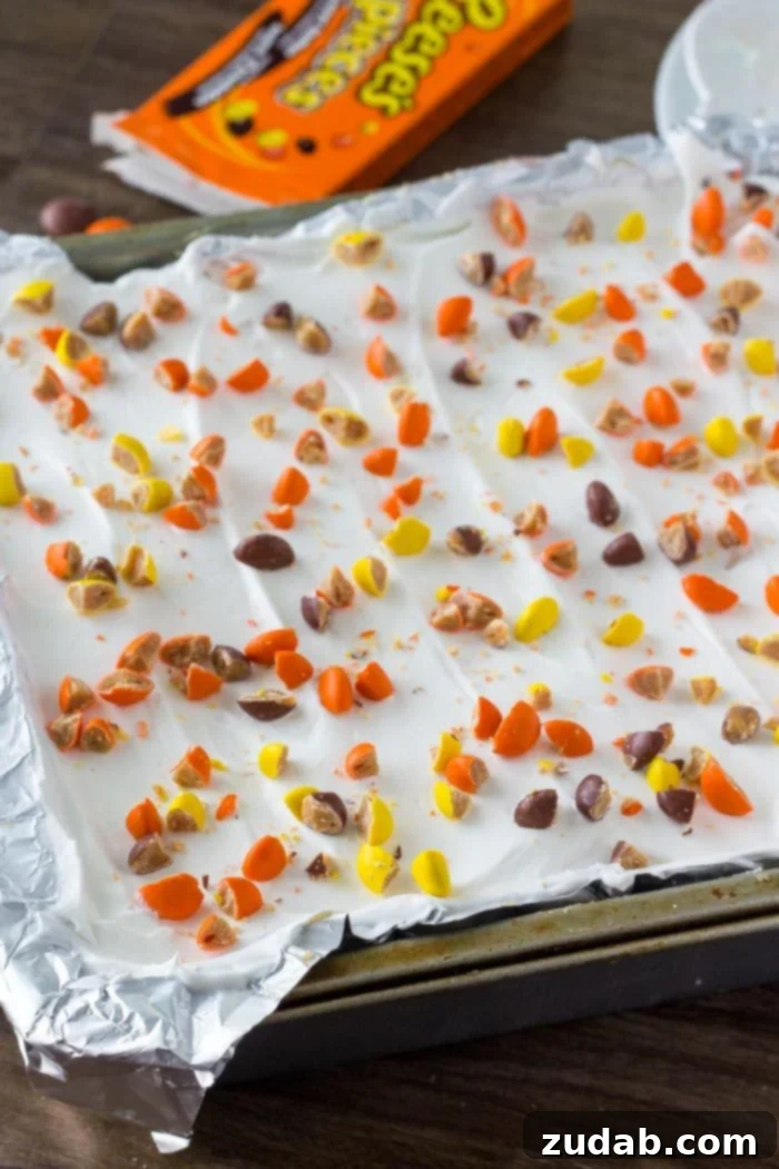 No-Bake Peanut Butter Dream 4 A decadent peanut butter icebox cake garnished with whipped topping and a generous scattering of peanut butter candies, ready to be chilled.