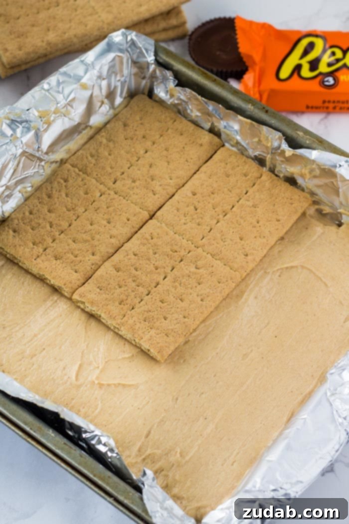 No-Bake Peanut Butter Dream 5 A close-up of a partially assembled peanut butter icebox cake, showing the rich filling and graham cracker layers before the final topping.