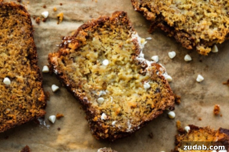 Moist White Chocolate Banana Bread 2 A slice of moist white chocolate banana bread on brown parchment paper, showing generous white chocolate chips.