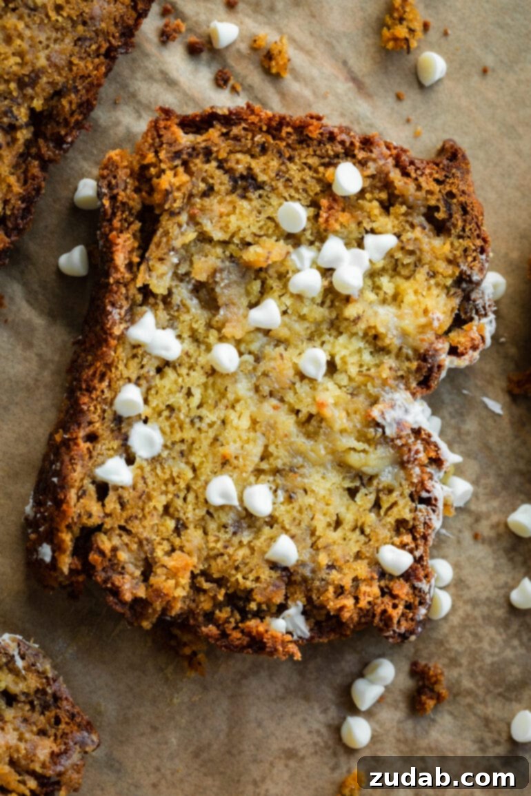 Moist White Chocolate Banana Bread 6 A piece of brown parchment paper with a slice of white chocolate chip banana bread on top.