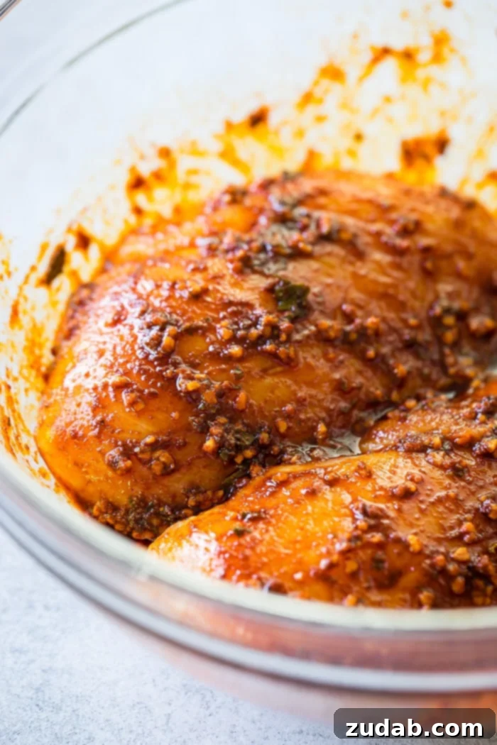Effortless Oregano Grilled Chicken 3 A glass bowl with chicken breasts that have been generously rubbed with a smoked paprika, garlic, and oregano spice blend, ready for grilling.
