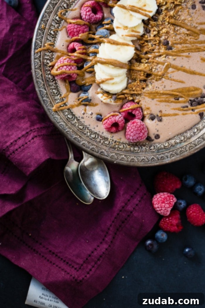 Chocolate Banana Smoothie Bowl Kids Love 4 Close-up of a rich chocolate smoothie bowl, beautifully garnished with fresh berries, sliced bananas, and crunchy granola, showcasing its tempting textures and vibrant colors. Ideal for a healthy kid-friendly meal.