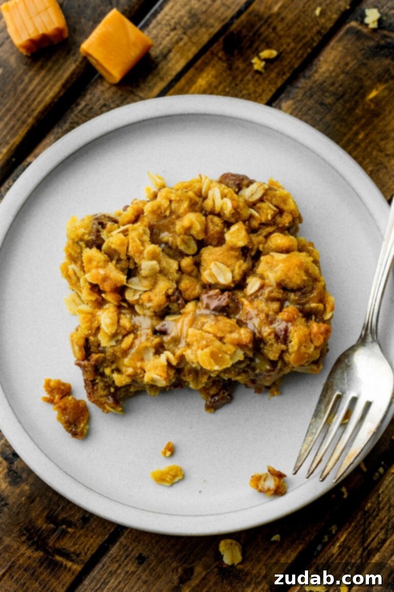 A photo taken from above a single Carmelita bar, showing its golden crumble topping with irresistible melty caramel and chocolate oozing out from the middle, emphasizing its decadent nature.