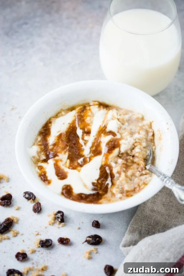 Guilt-Free Cinnamon Swirl Oats 5 A steaming bowl of lightened up cinnamon roll oatmeal, topped with swirls of cinnamon filling and a white yogurt glaze, served on a rustic wooden surface