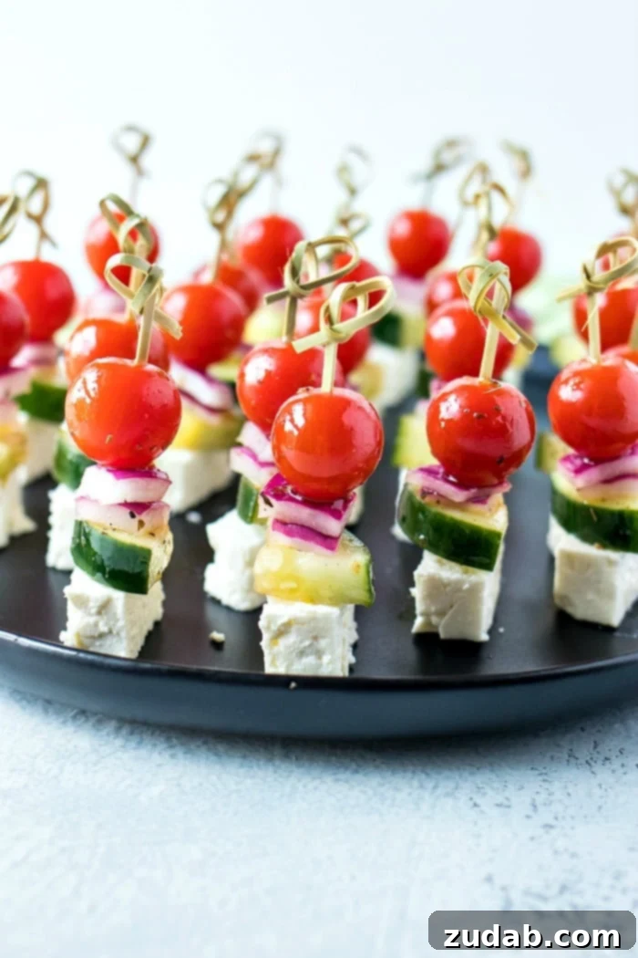 Mediterranean Mezze Skewers 3 Three Greek Salad Skewers featuring cherry tomatoes, cucumber, red onion, and feta cheese, marinated in Greek vinaigrette, artfully arranged.