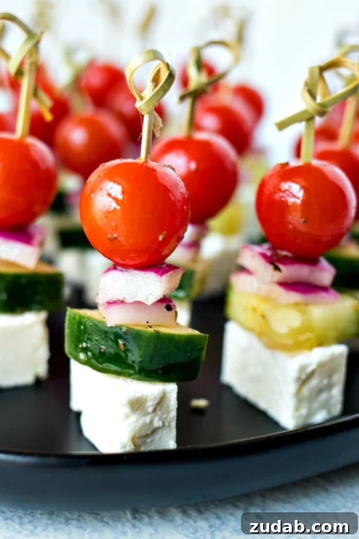Mediterranean Mezze Skewers 4 Close-up of a vibrant Greek Salad Skewer, highlighting the fresh cherry tomatoes, cucumber slices, red onion, and a cube of feta cheese, all glistening with vinaigrette.