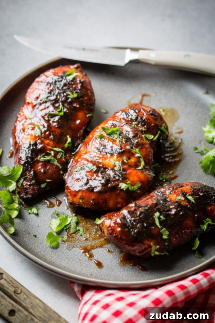 Smoky Grilled BBQ Chicken Bliss 5 A grey plate with multiple grilled bbq sauce chicken breasts sprinkled with cilantro that has been chopped