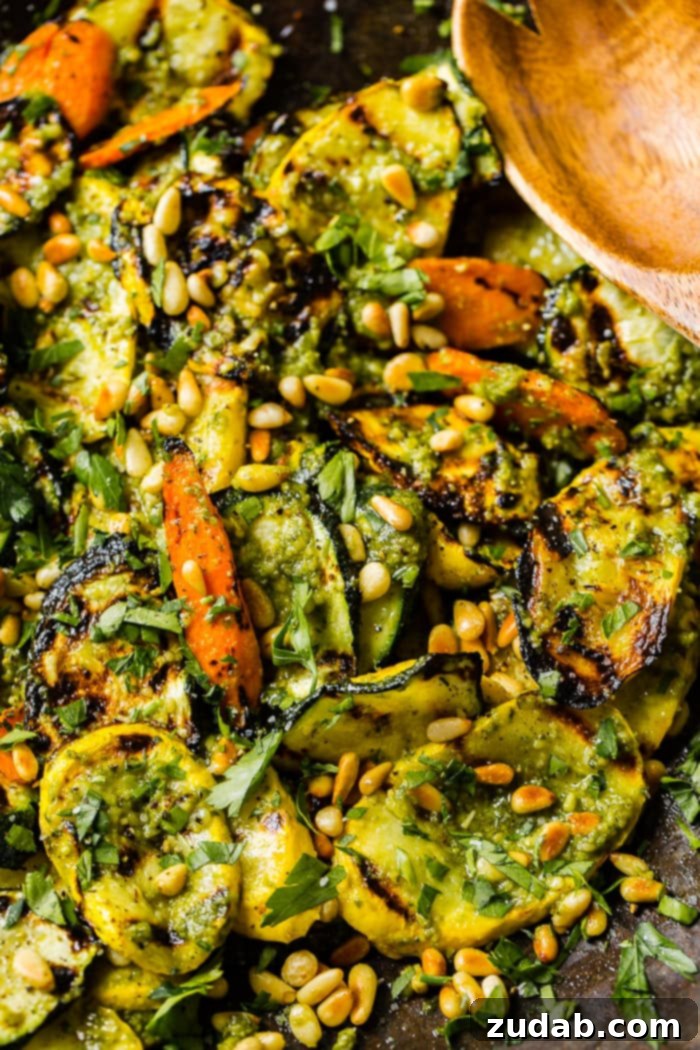 Easy 15-Minute Pesto Grilled Veggies 2 A close up of grilled veggies with pesto, parsley and toasted pine nuts including zucchini, yellow squash and carrots for a 15 minute grilled veggies with pesto recipe