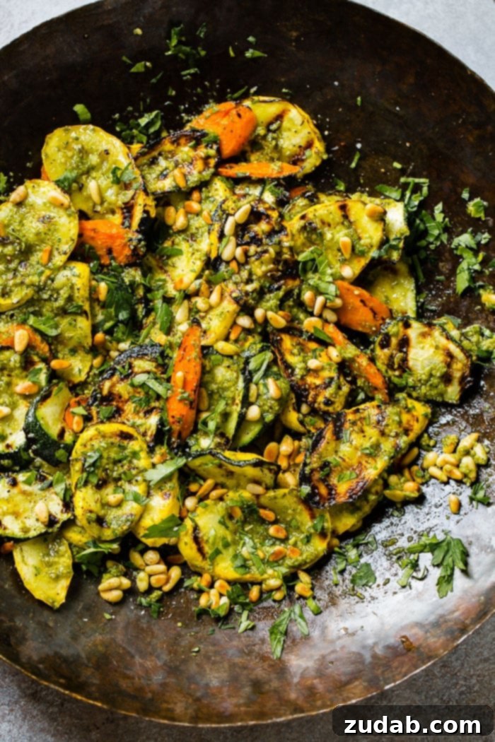 Easy 15-Minute Pesto Grilled Veggies 3 A close up of grilled veggies with pesto, parsley and toasted pine nuts including zucchini, yellow squash and carrots for a 15 minute grilled veggies with pesto recipe