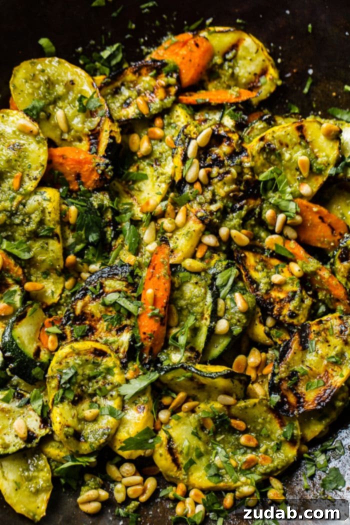 Easy 15-Minute Pesto Grilled Veggies 4 A close up of grilled veggies with pesto, parsley and toasted pine nuts including zucchini, yellow squash and carrots for a 15 minute grilled veggies with pesto recipe